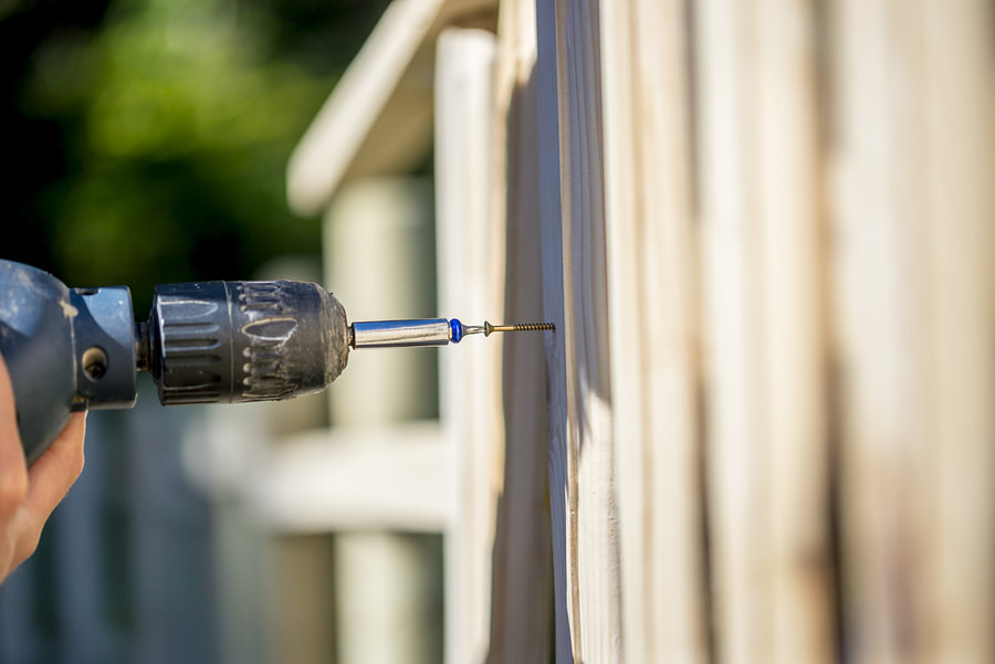 man drilling on a fence